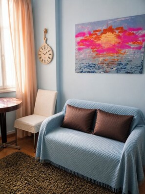 A room with a blue sofa, a clock, a painting, and a table. - HOME FOR 2 FEW STEPS FROM CASINO MONTE CARLO AND BEACH (Beausoleil)