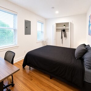 A bedroom with a bed, a desk, and a closet. - Enjoy a relaxed stay in this well-kept unit offering free parking, a stocked kitchen, and an in-suite washer/dryer. Great for work or leisure trips. (Rochester)