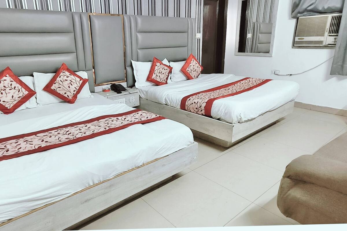 Habitación de hotel con dos camas, un sofá, una mesita de noche y un espejo.
