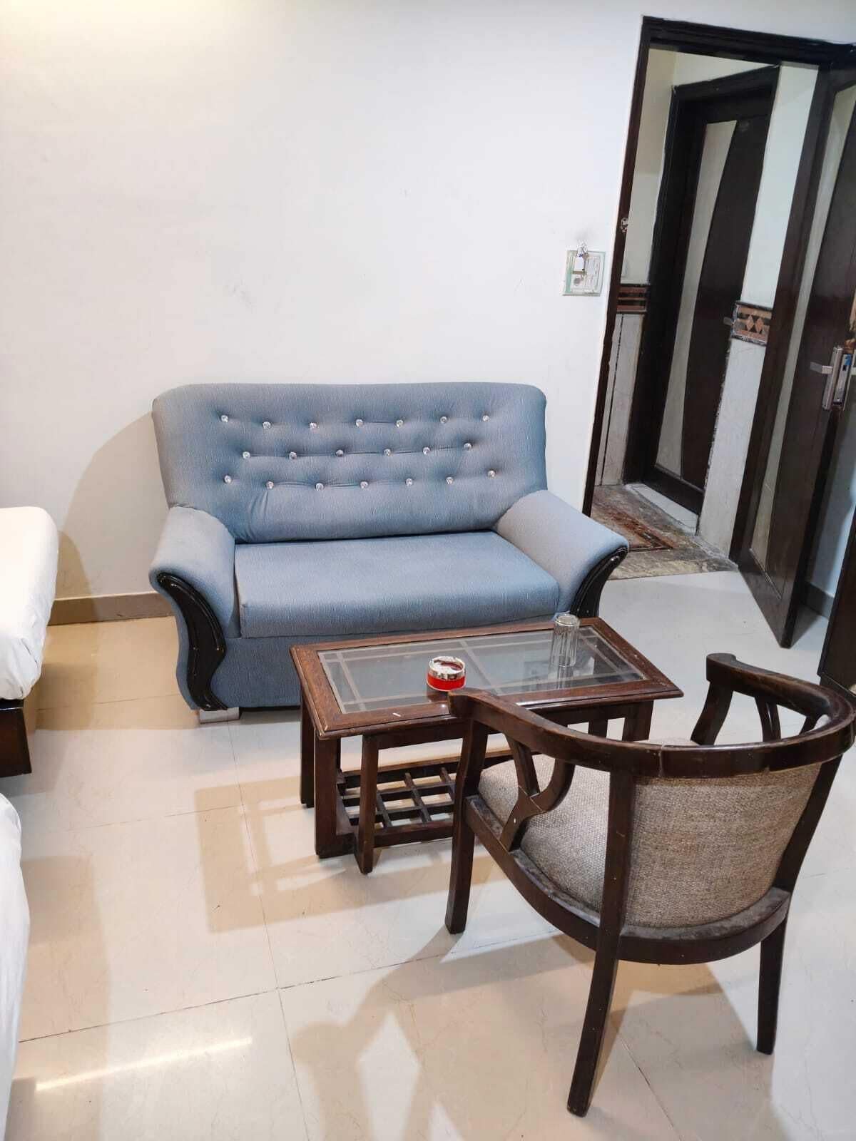 A living room with a blue sofa, a glass coffee table, and a wooden chair.