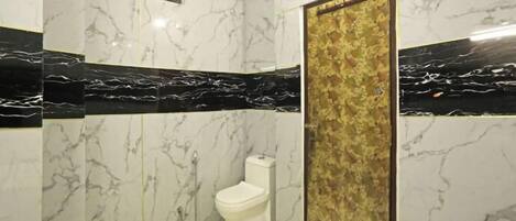 Een badkamer met marmeren wanden, een wit toilet en een douchegedeelte.