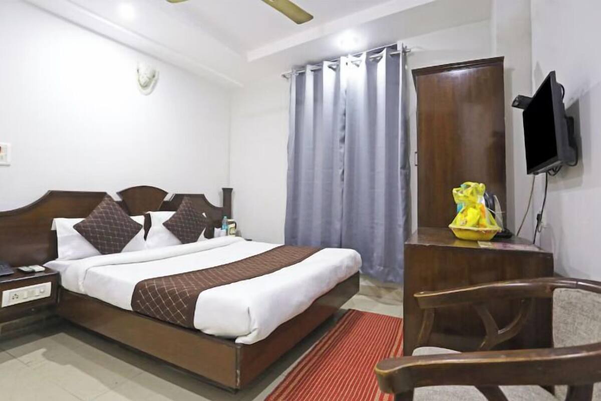 Habitación de hotel con cama, escritorio, silla, televisor y armario.