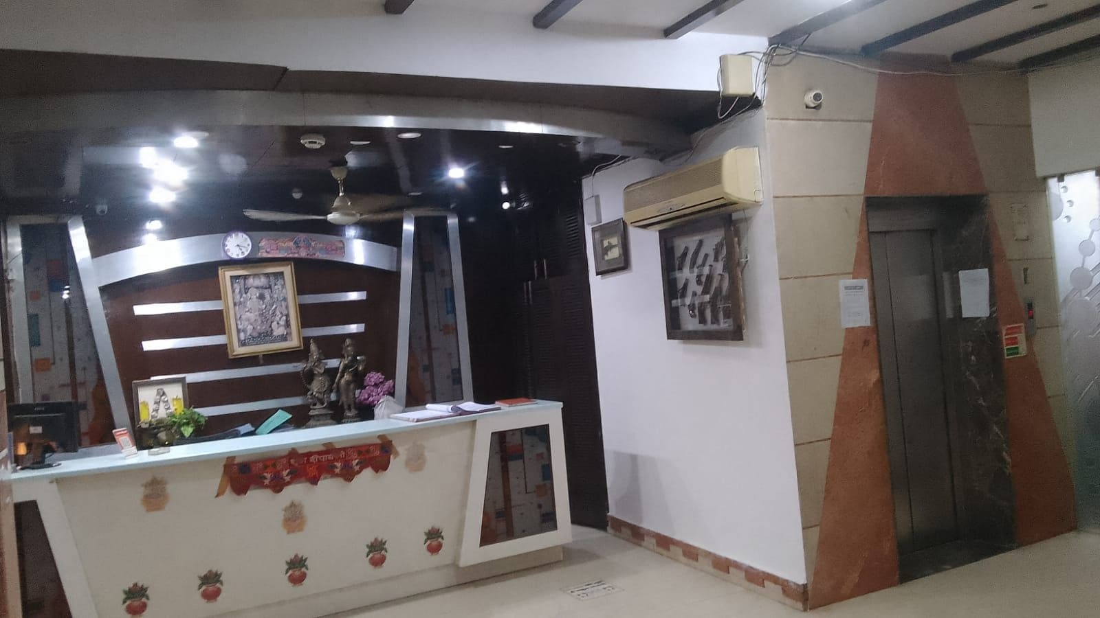 Un mostrador de recepción con un reloj, cuadros enmarcados y una pequeña estatua.
