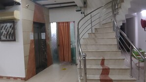 Una escalera con barandillas de metal y pasamanos, que conduce a un ascensor.
