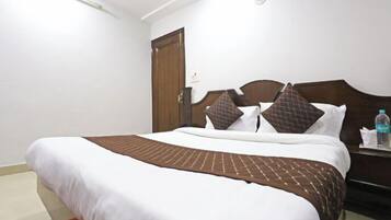 Ein Hotelzimmer mit einem Bett, einem Holzkopfteil, einem Nachttisch und einer Tür.
