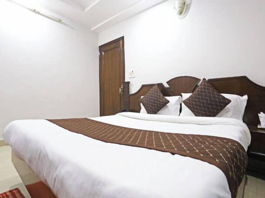Ein Hotelzimmer mit einem Bett, einem Holzkopfteil, einem Nachttisch und einer Tür.