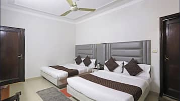A hotel room with two beds, a ceiling fan, a desk, and a door.