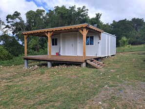 Ein kleines, eingeschossiges Gebäude mit einer Holzterrasse und einer überdachten Veranda.