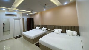 A modern hotel room with two beds, a ceiling fan, recessed lighting, and an air conditioning unit. - Awesome 9-bedroom hotel with AC in vibrant Varanasi (Varanasi)