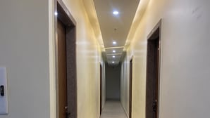 A long, narrow hallway with doors on both sides, recessed ceiling lighting, and a tiled floor. - Awesome 9-bedroom hotel with AC in vibrant Varanasi (Varanasi)