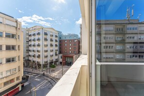 Ein mehrstöckiges Gebäude mit Balkonen, eine Straße davor und ein klarer Himmel.