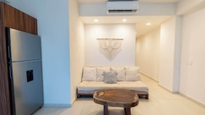 Uma sala de estar moderna com um sofá, uma mesa de centro de madeira e um sistema de ar condicionado embutido.