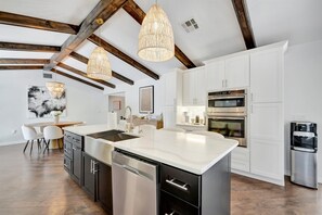 Cozinha moderna com armários brancos, eletrodomésticos de aço inoxidável e uma ilha grande.