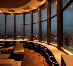 A high-rise interior with a curved seating area, large windows, and a cityscape view. - Berrini Retreat Beautiful 1 BR in S o Paulo (São Paulo)