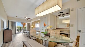 Ein modernes Hotelzimmer mit einem Glastisch, bequemen Sitzmöglichkeiten, einem Deckenventilator und Blick ins Freie.