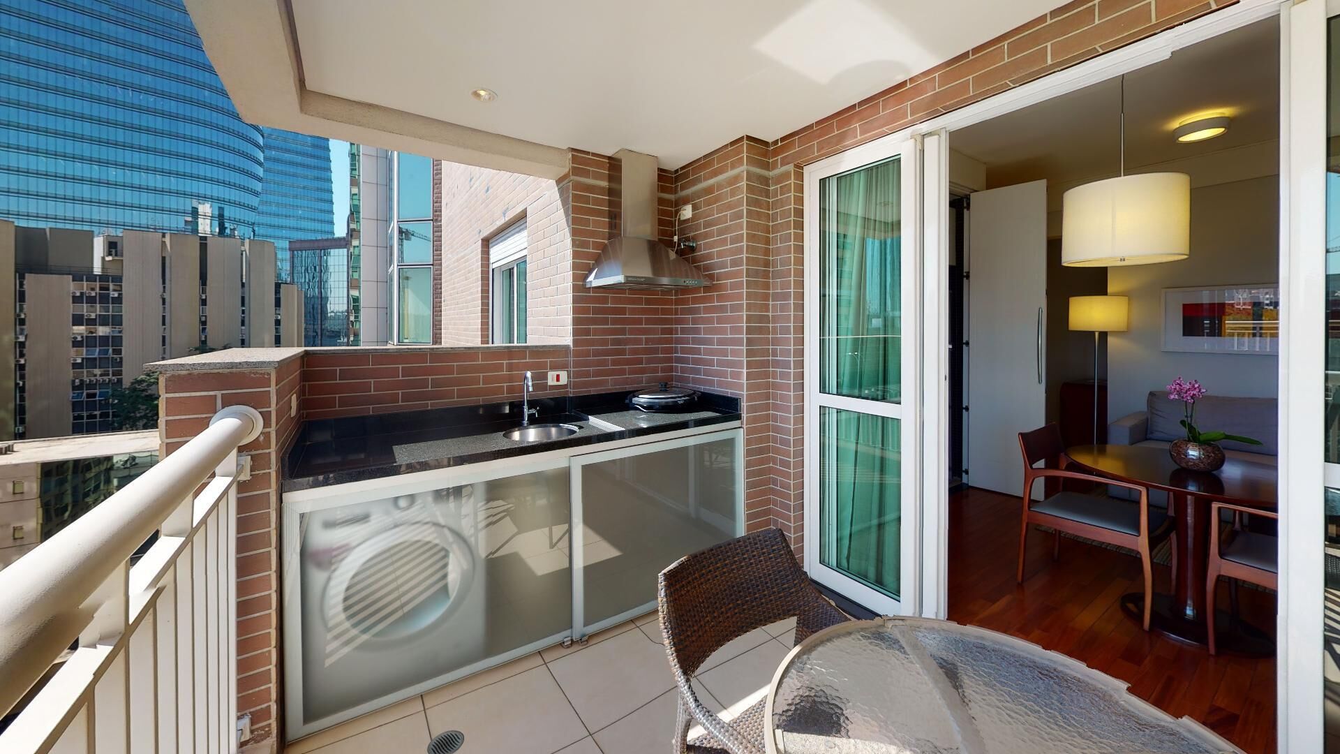 Un balcón con cocina, una mesa de comedor y una silla.