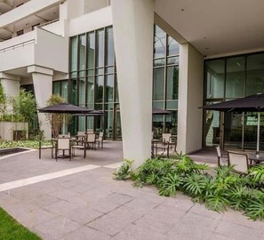 A modern building with large windows, outdoor seating, and a garden area. - Berrini Mood Beautiful 1 BR in S o Paulo (São Paulo)
