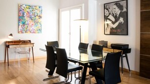 A modern dining area with a glass table, black chairs, a piano, and artwork on the walls. - El Jacaranda Large 3 BR With Balcony in Recoleta (Buenos Aires)