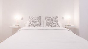 A bed with white bedding, two nightstands with lamps, and two pillows with a floral pattern. - Republica 2BR apt Near Madrid s Financial Center (Madrid)