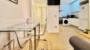 A modern kitchen with a washing machine, a dining area with a glass table, and a living space with a sofa. - Republica 2BR apt Near Madrid s Financial Center (Madrid)