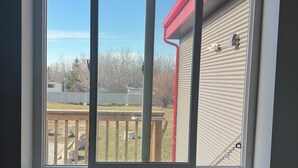 A window with a view of a backyard, a red roof, and a white exterior wall. - Richer Esso and Motel (Richer)