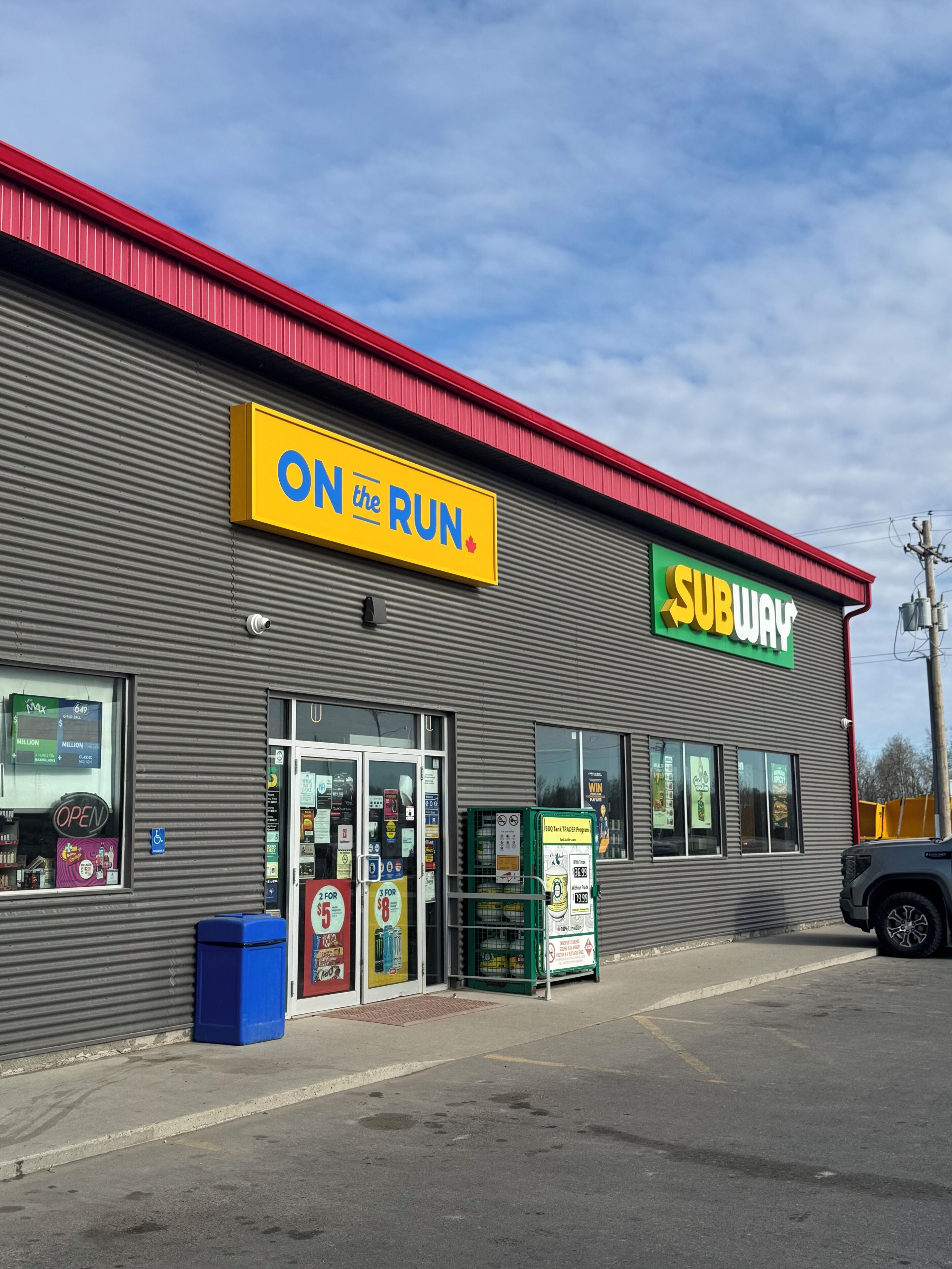 A SUBWAY restaurant with a sign reading 'ON the RUN' and a parking lot in front.