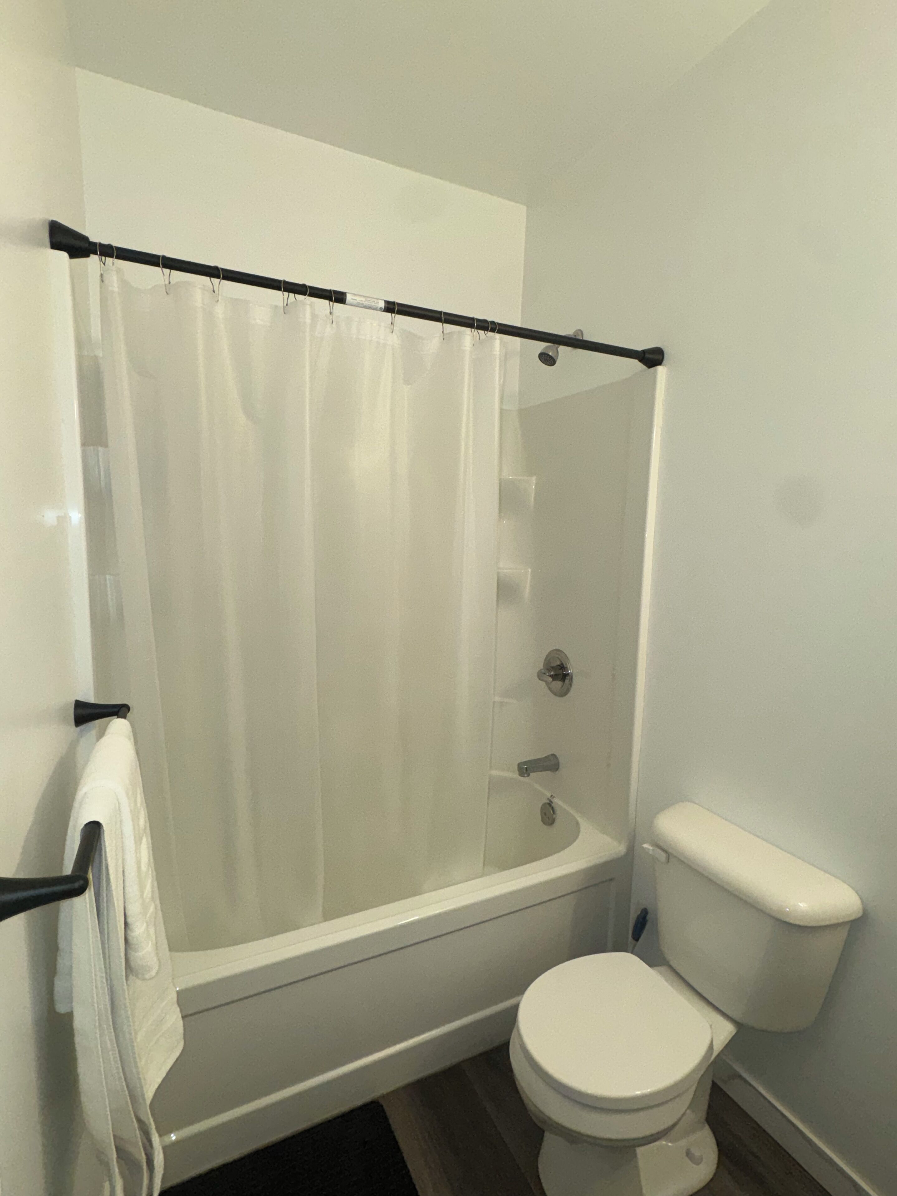 A bathroom with a bathtub, toilet, and a shower curtain.