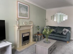 Ein Wohnzimmer mit Kamin, einem gerahmten Kunstwerk, einem modernen Sofa und einem Couchtisch.