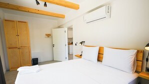 Een slaapkamer met een bed, een houten garderobe en een wandairconditioner.