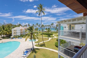 A resort with a swimming pool, palm trees, and a view of the ocean. - Playa Turquesa K403_200Mbps_Private Beach Access_Rooftop (Bavaro-Punta Cana)