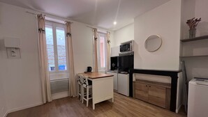 Uma cozinha compacta com área de refeições, micro-ondas, geladeira e uma pequena mesa com cadeiras.
