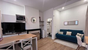Um espaço compacto com cozinha compacta, área de refeições e sala de estar com sofá.