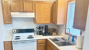 A kitchen with wooden cabinets, a white stove, and a sink. - Find comfort in this cozy, recently updated apartment. Featuring two bedrooms, a full kitchen with oak cabinets, and a generous living space. It's designed for easy living with a ranch-style, step-up entry. Located in a peaceful neighborhood. (Marion)