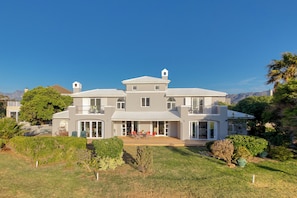 A two-story house with a balcony, a patio with outdoor furniture, and a well-maintained lawn.