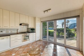 A modern kitchen with white cabinets, stainless steel appliances, and a large sliding glass door leading to a deck.