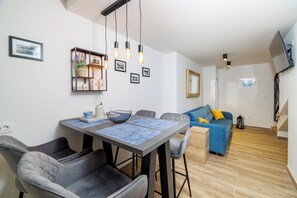 Ein modernes Wohnzimmer mit Essbereich, einer Couch und einem an der Wand befestigten Fernseher.