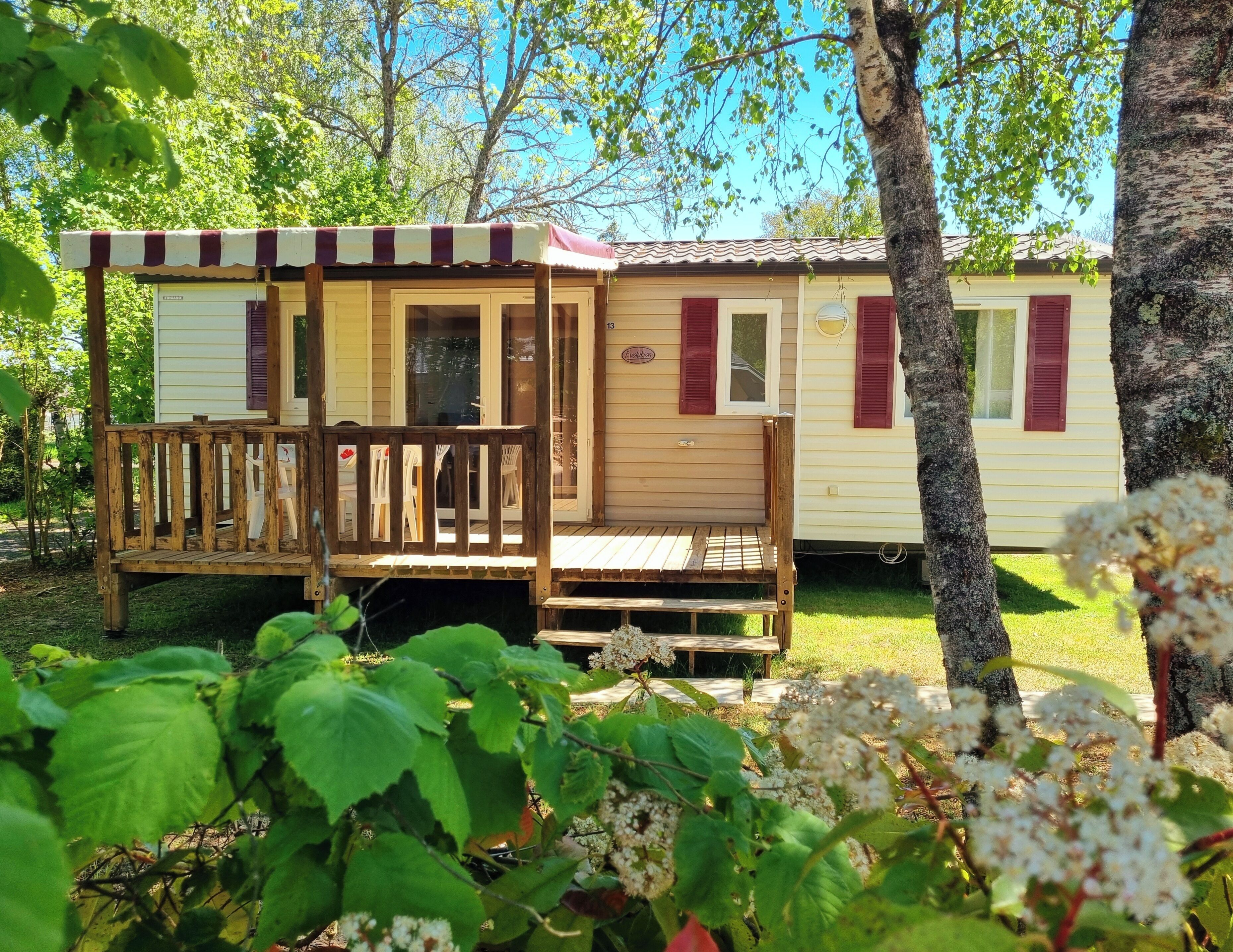 A wooden cabin with a porch, a small deck, and a window with shutters.