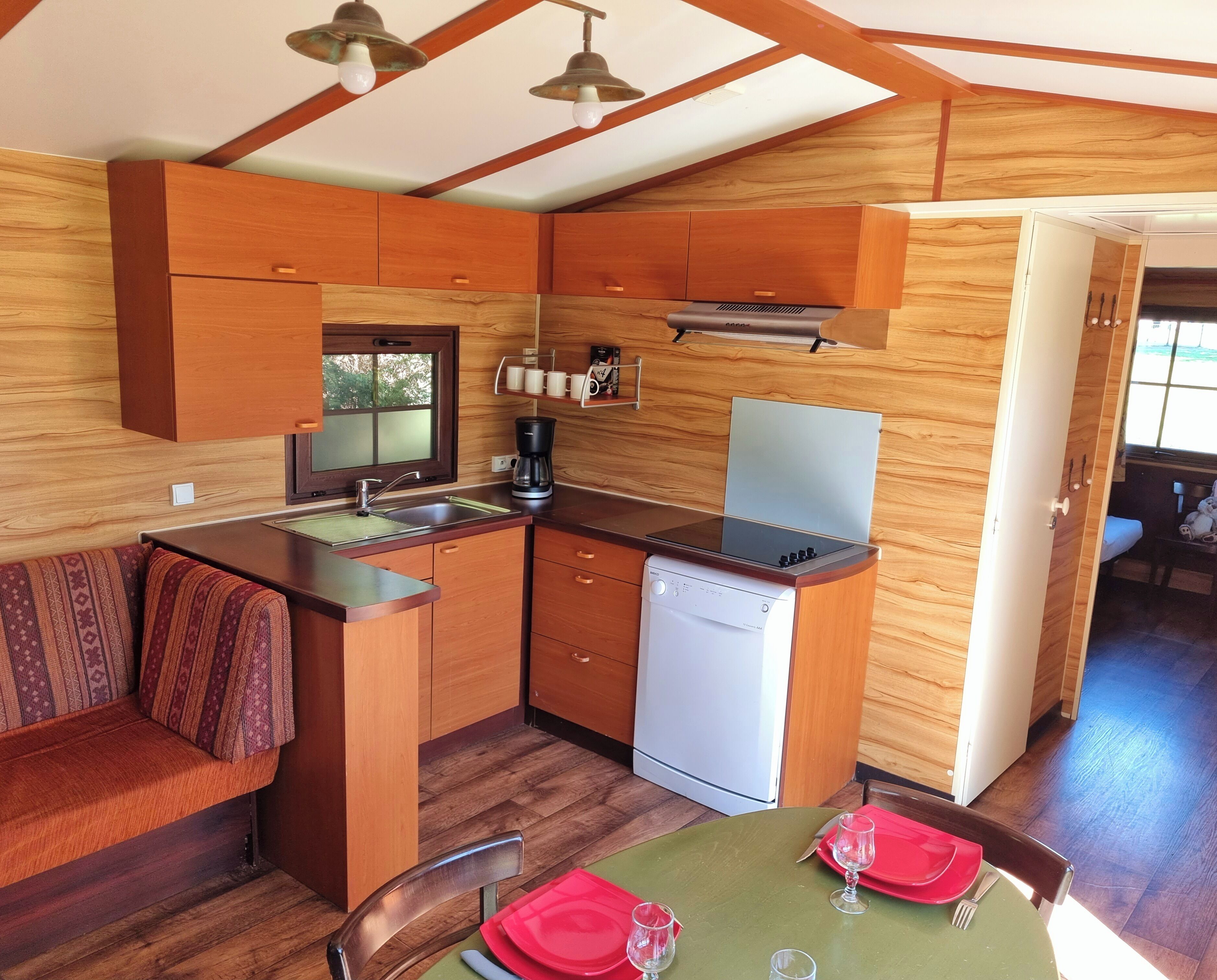 A compact kitchen with wooden cabinetry, a built-in dishwasher, and a coffee maker.