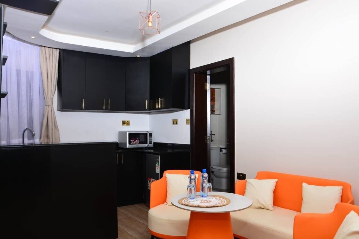 A compact room with a kitchenette, a sofa, and a small table with water bottles.