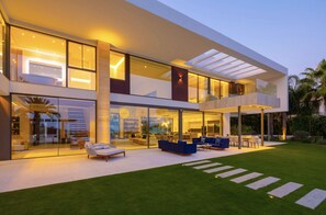 Ein modernes Haus mit großzügigem Außenbereich, großen Fenstern und einem gepflegten Rasen.