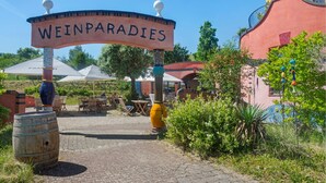 Une enseigne indiquant « WEINPARADIES », avec des tables à l’extérieur et un tonneau rustique.