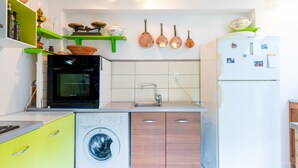 A compact kitchen with a washing machine, oven, and a refrigerator.
