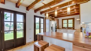 Eine moderne Küche mit Holzbalken, großen Fenstern und einer zentralen Kochinsel mit Sitzgelegenheiten.
