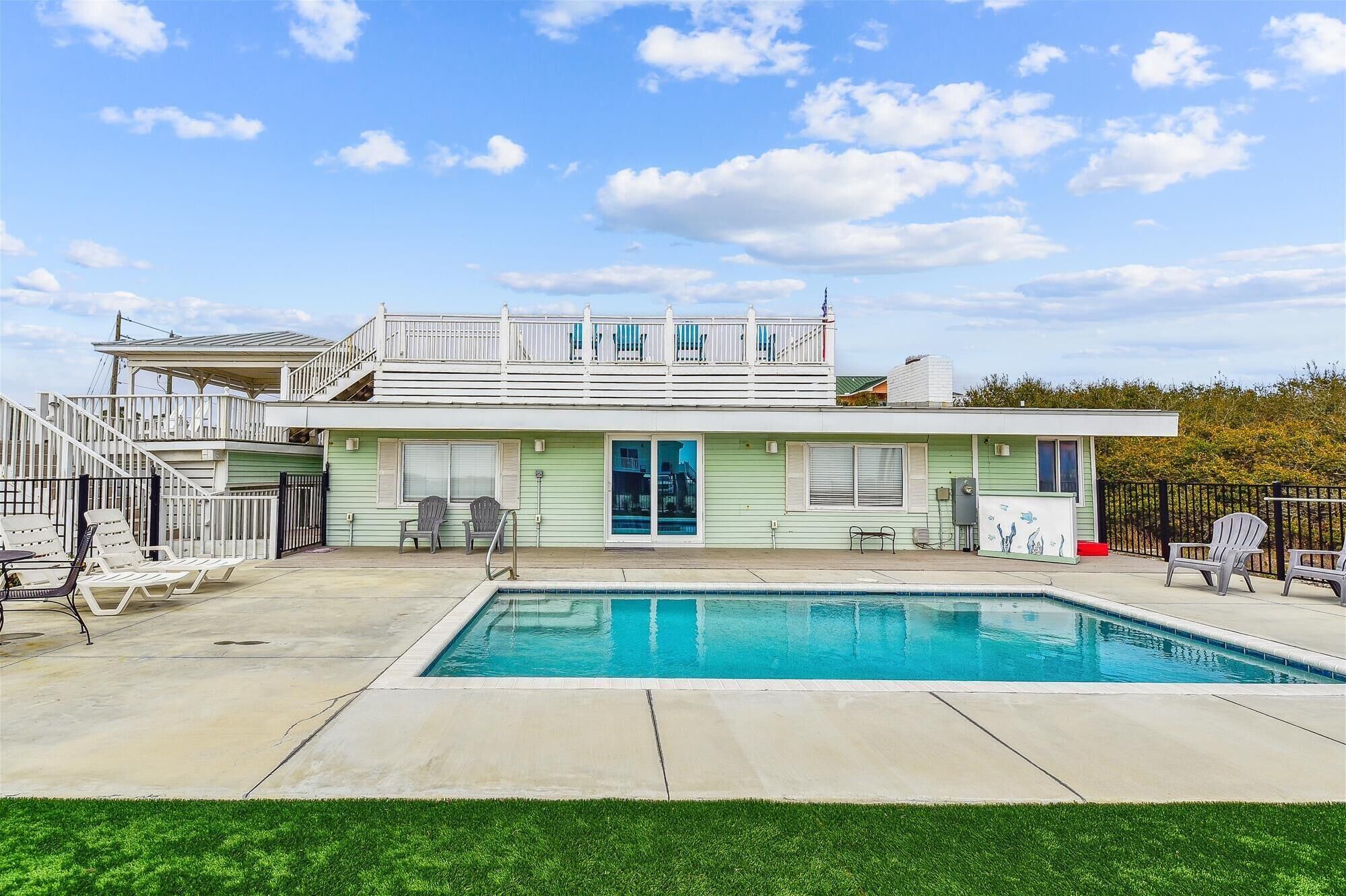 A two-story house with a swimming pool, a covered patio, and a fenced backyard.