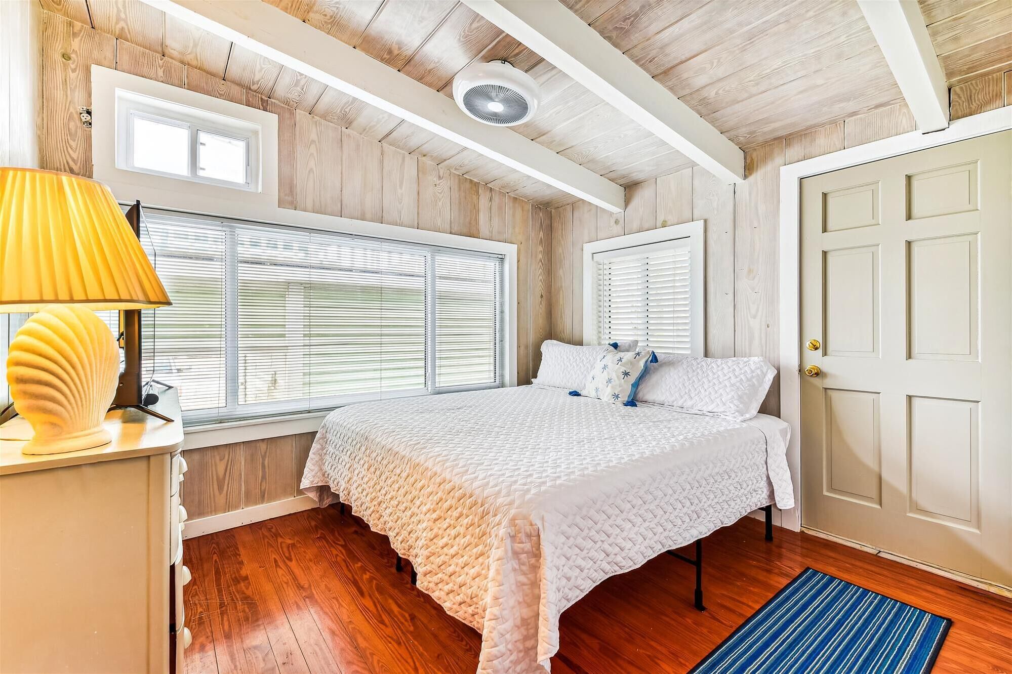A bedroom with a bed, a bedside lamp, and a door.