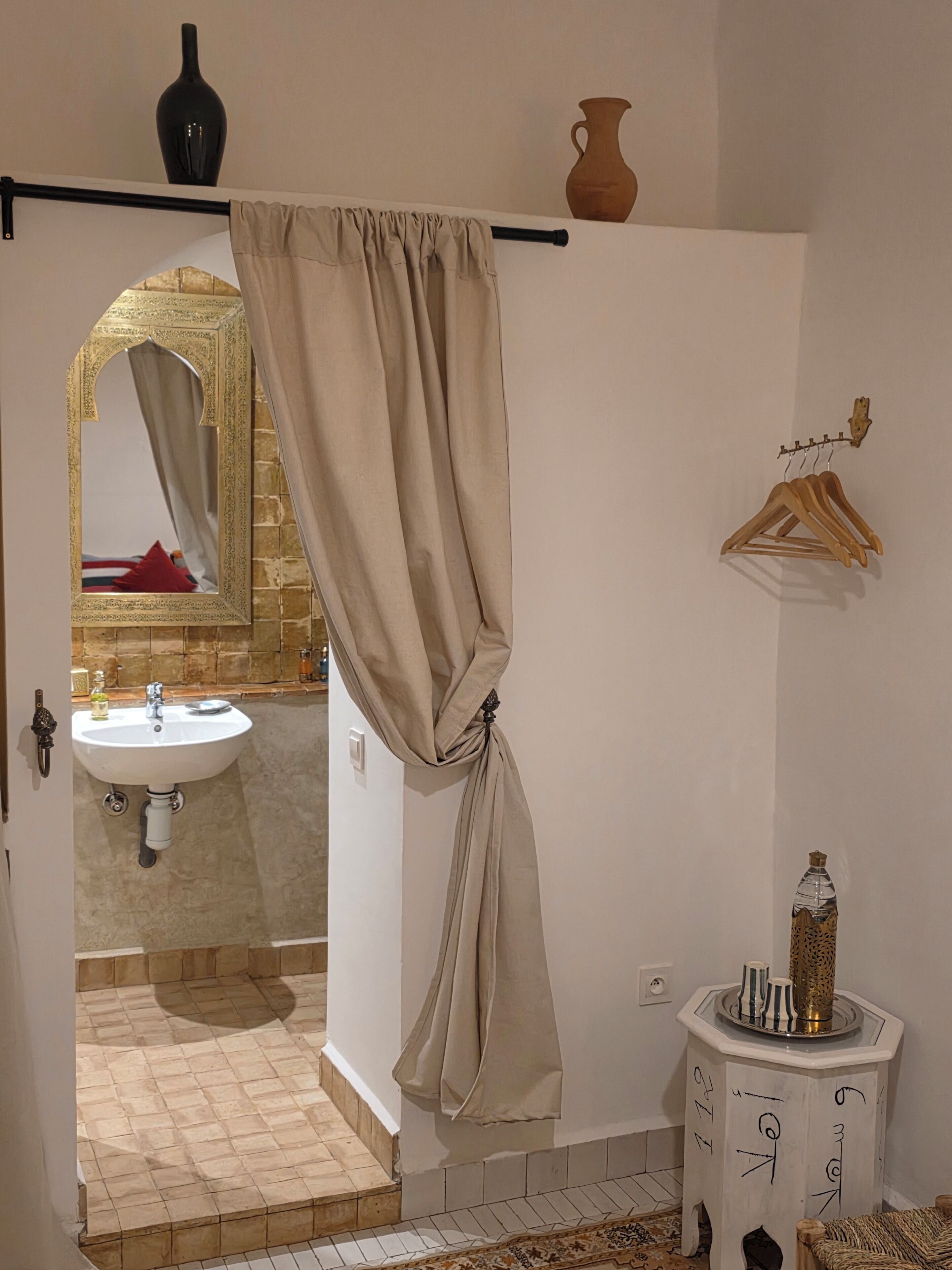 Un baño con lavamanos, espejo y toallero.