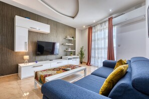 A modern living room with a flat-screen TV, a sofa, a coffee table, and a TV stand. - Modern and cosy 2 bedroom apartment PSCI1-1 (Mellieha)