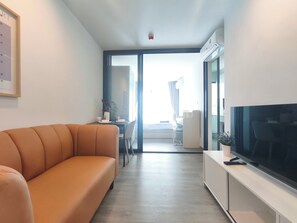 A modern living room with a sofa, a flat-screen TV, and a dining area with a table and chairs.