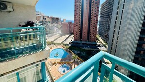 Un edificio de gran altura con varios pisos, una piscina en la azotea y vistas del área urbana circundante.
