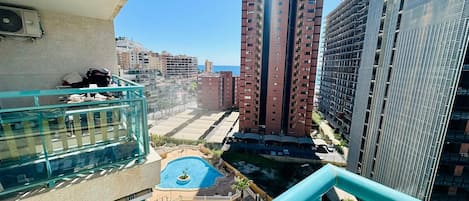 A high-rise building with multiple floors, a rooftop pool, and a view of the surrounding urban area.